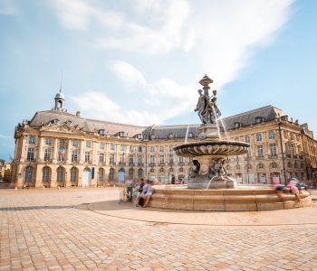 View on the famous La Bourse square with fountain in Bordeaux city, France. Long exposure image technic with motion blurred people and clouds