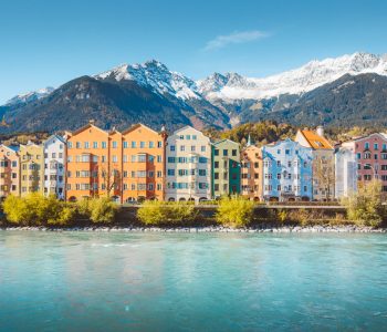 Panoramic view of the historic city center of Innsbruck with colorful houses along Inn river and famous Austrian mountain summits in the background in beautiful evening light at sunset, Tyrol, Austria